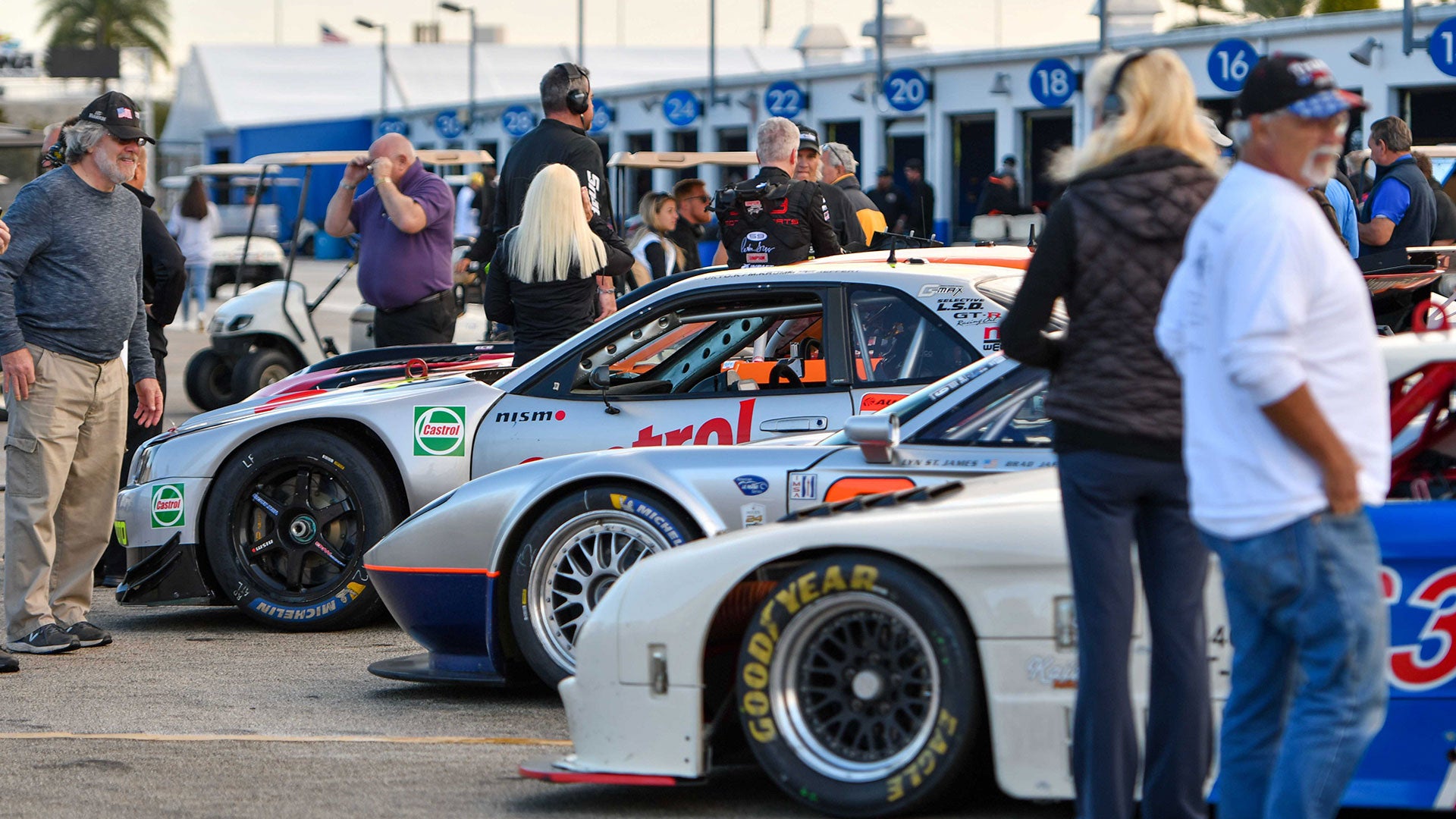 Collection of historic race cars surrounded by people